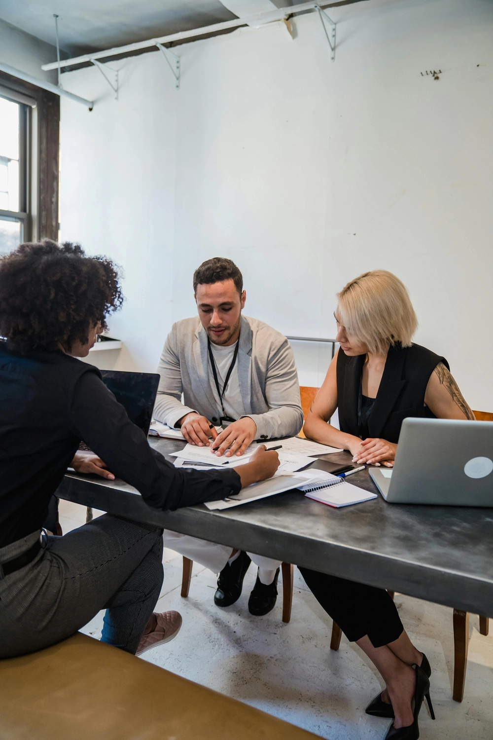 GP ORGAPLAN – Organisationsplanung und Strukturlösungen – Dieses Bild zeigt ein professionelles Geschäftstreffen mit einem diversen Team, das in einem modernen Büro an einem Tisch zusammenarbeitet.