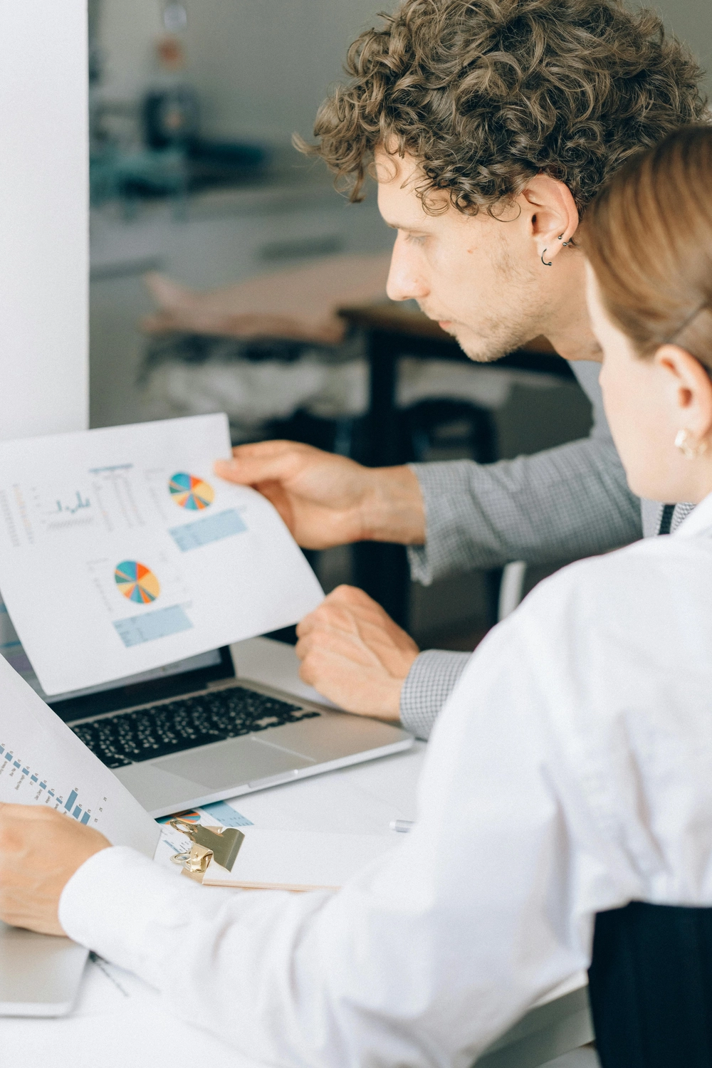 GP ORGAPLAN – Organisationsplanung und Strukturlösungen – Dieses Bild zeigt zwei Fachkräfte, die gemeinsam Datenanalysen und Finanzberichte an einem Schreibtisch auswerten.
